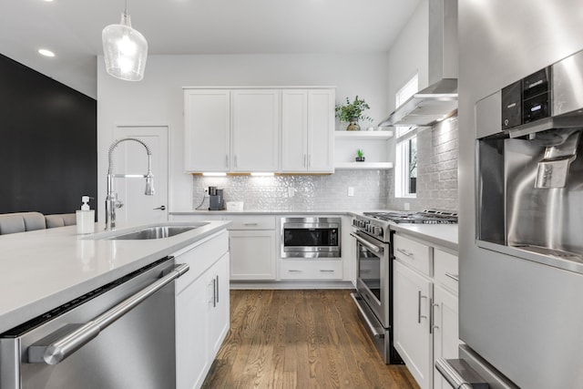 kitchen with a sink, white cabinetry, light countertops, wall chimney range hood, and appliances with stainless steel finishes