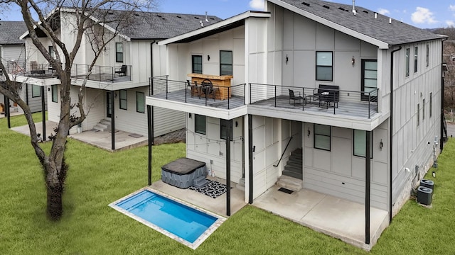 back of property with a shingled roof, a lawn, a patio, a balcony, and board and batten siding