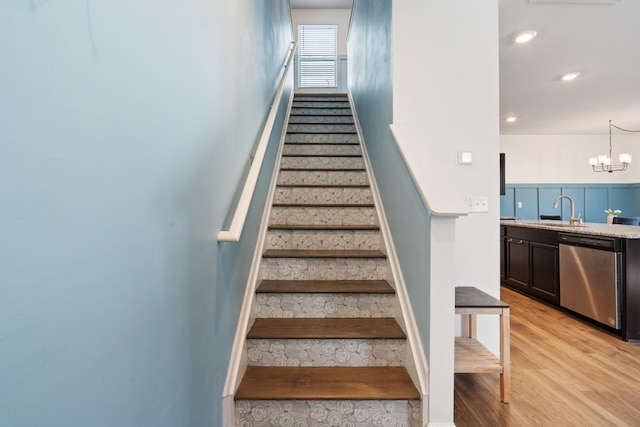 stairway with a notable chandelier, wood finished floors, and recessed lighting