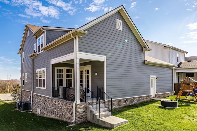 back of property featuring a playground, a lawn, and central AC unit