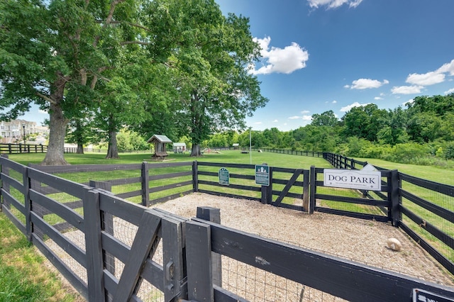 view of gate featuring a rural view, fence, and a yard