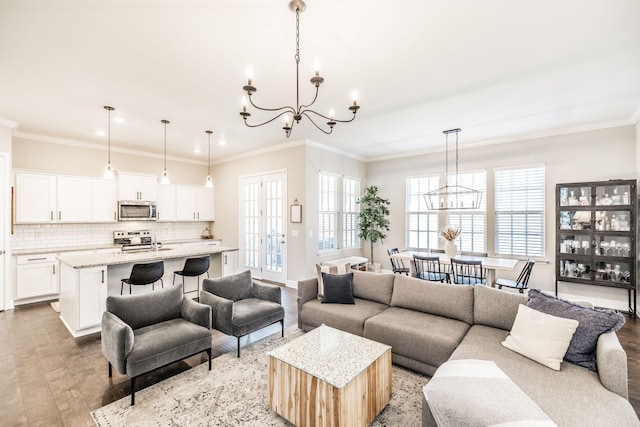 living room with a chandelier, crown molding, and a healthy amount of sunlight