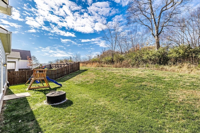 view of yard featuring an outdoor fire pit, a playground, and a fenced backyard