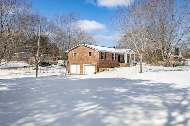 view of snowy exterior featuring brick siding and an attached garage