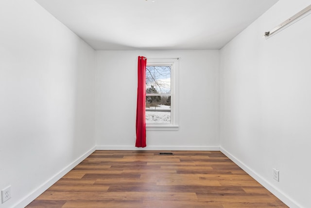 unfurnished room with dark wood-style floors, visible vents, and baseboards