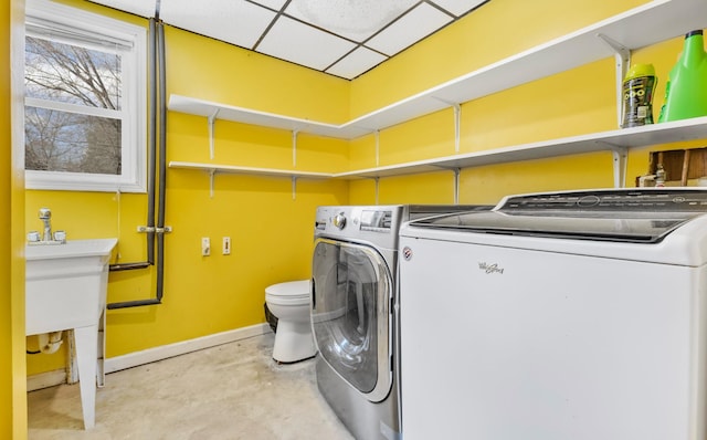 laundry area with separate washer and dryer and baseboards