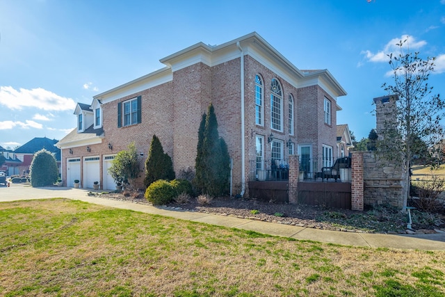 view of side of home featuring a garage, a yard, concrete driveway, and brick siding