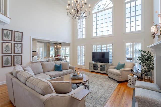 living room featuring an inviting chandelier, baseboards, and wood finished floors