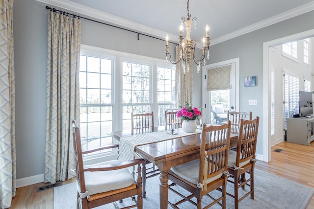 dining space featuring light wood-style floors, ornamental molding, a chandelier, and a wealth of natural light