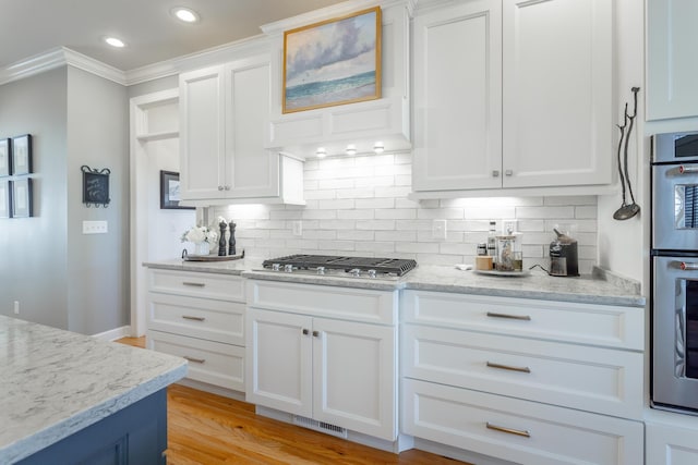 kitchen with tasteful backsplash, visible vents, appliances with stainless steel finishes, white cabinets, and light stone countertops