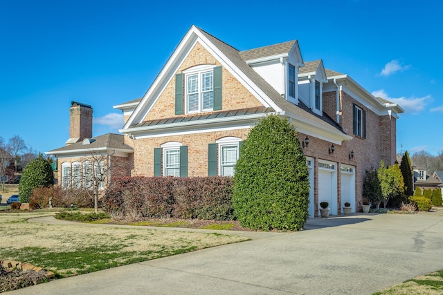 view of front of home featuring a garage, driveway, brick siding, a standing seam roof, and a front yard