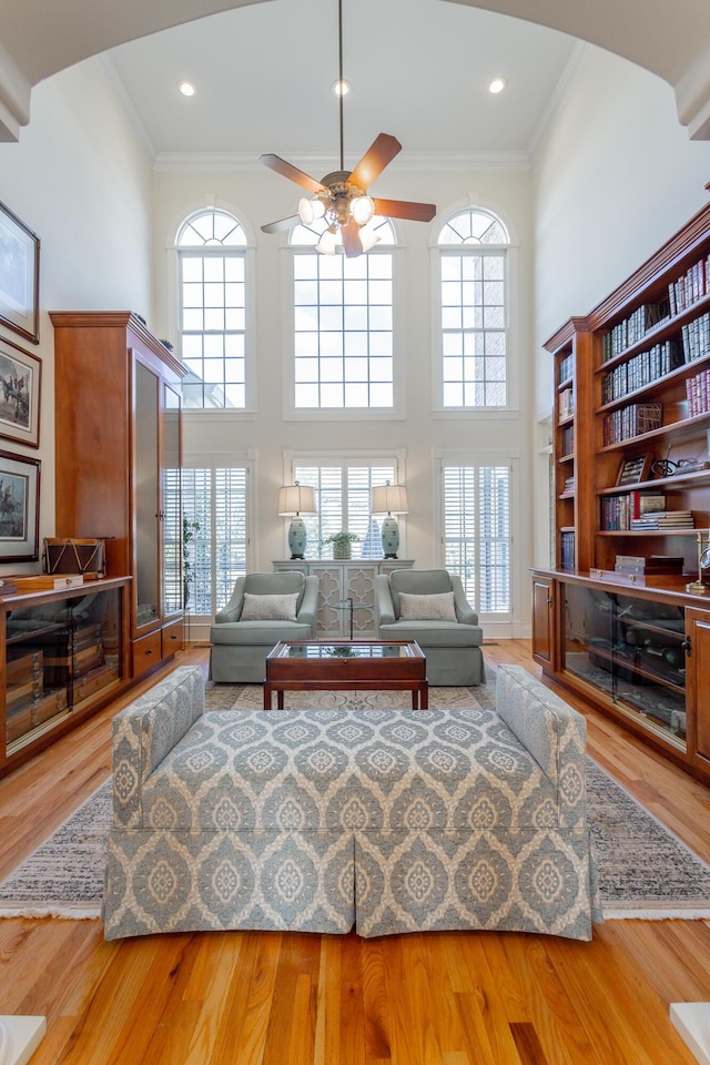 living area featuring ornamental molding, a ceiling fan, a healthy amount of sunlight, and wood finished floors