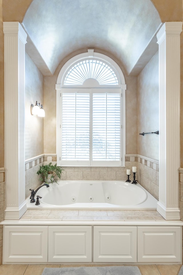 full bathroom with ornate columns, a tub with jets, and vaulted ceiling