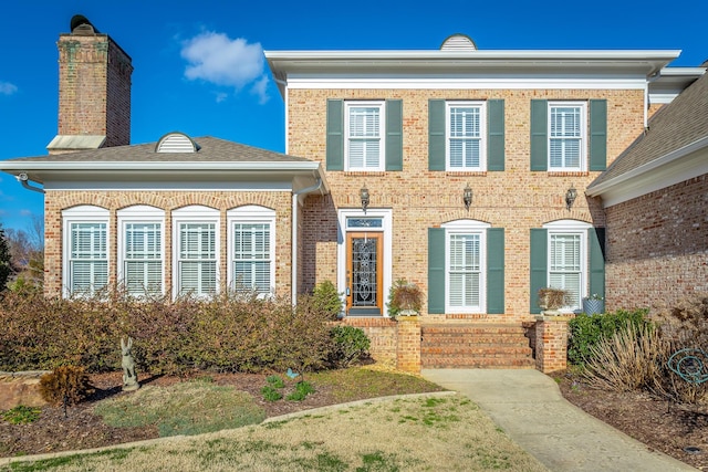 view of front of property featuring brick siding and a chimney