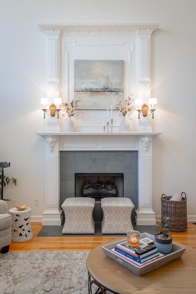 interior space featuring baseboards, a tiled fireplace, and wood finished floors