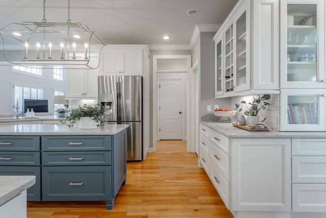 kitchen featuring light wood-style flooring, white cabinetry, stainless steel refrigerator with ice dispenser, glass insert cabinets, and pendant lighting