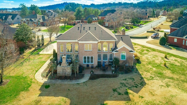 rear view of property with a patio, brick siding, a chimney, and a residential view