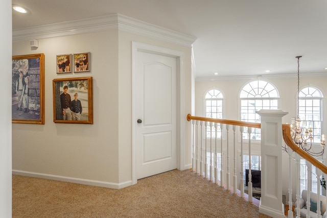 hall with baseboards, ornamental molding, carpet flooring, and an inviting chandelier