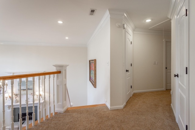 hallway with baseboards, ornamental molding, attic access, and light colored carpet