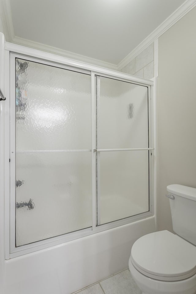 bathroom featuring toilet, combined bath / shower with glass door, crown molding, and tile patterned floors