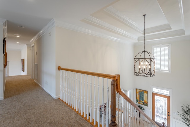 hall featuring crown molding, an upstairs landing, carpet, a raised ceiling, and an inviting chandelier