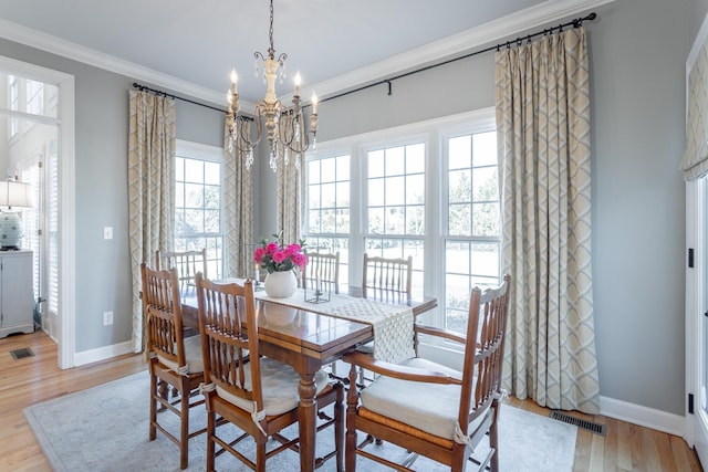 dining area featuring light wood-type flooring, a wealth of natural light, visible vents, and crown molding