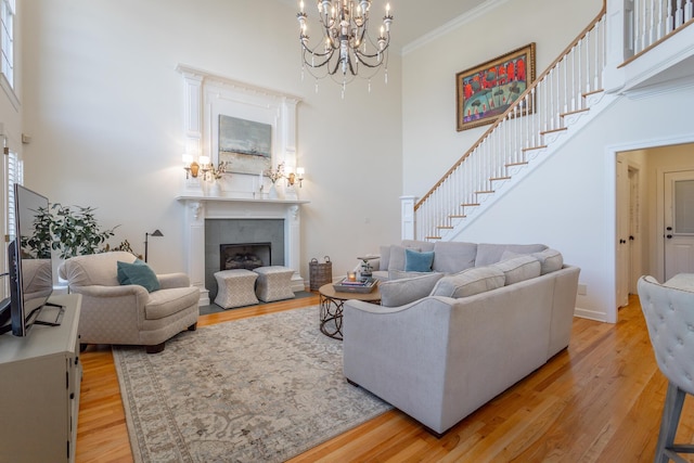 living area featuring a fireplace, stairway, a high ceiling, ornamental molding, and wood finished floors