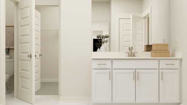 bathroom with a walk in closet, baseboards, vanity, and toilet