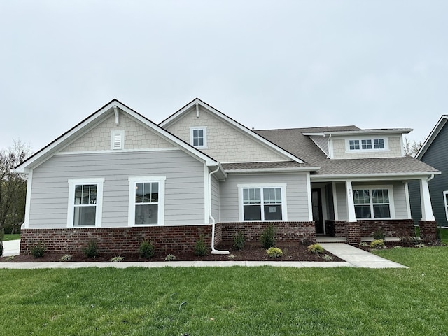 craftsman house featuring a front yard and brick siding