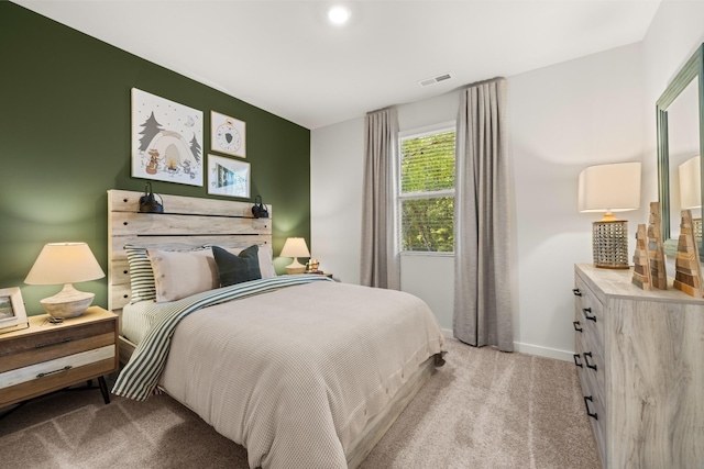 bedroom with baseboards, visible vents, and light colored carpet