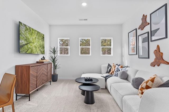 living room with a wealth of natural light, visible vents, carpet floors, and baseboards