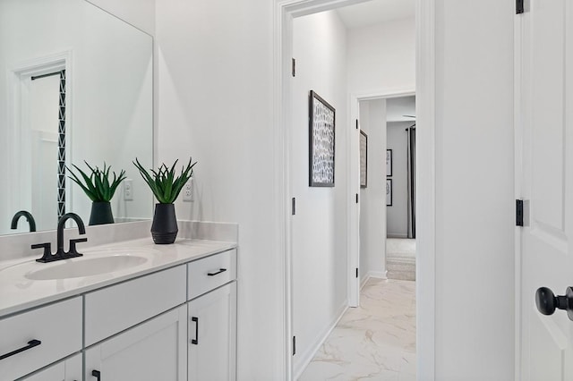 bathroom featuring baseboards, marble finish floor, and vanity