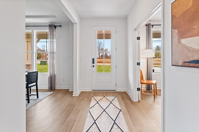 entryway featuring light wood-style flooring, baseboards, and a wealth of natural light