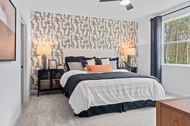 carpeted bedroom with multiple windows, wallpapered walls, an accent wall, and baseboards