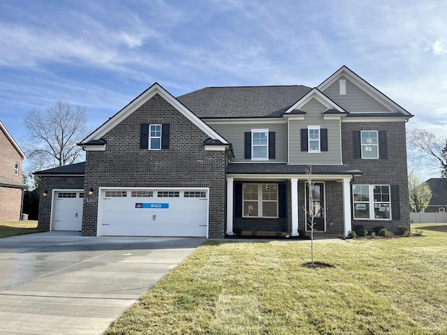 traditional home featuring a shingled roof, concrete driveway, an attached garage, a front yard, and brick siding