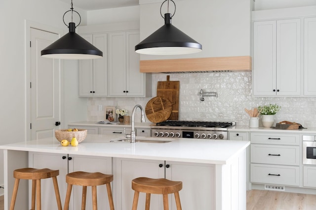 kitchen featuring light countertops, stainless steel gas stovetop, white cabinets, a sink, and a kitchen breakfast bar