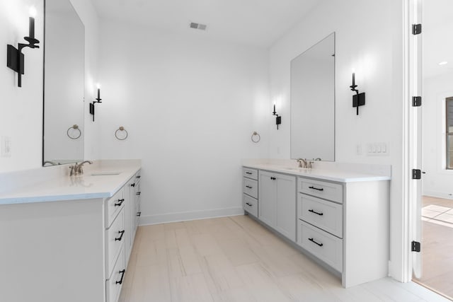 bathroom with a sink, baseboards, visible vents, and two vanities