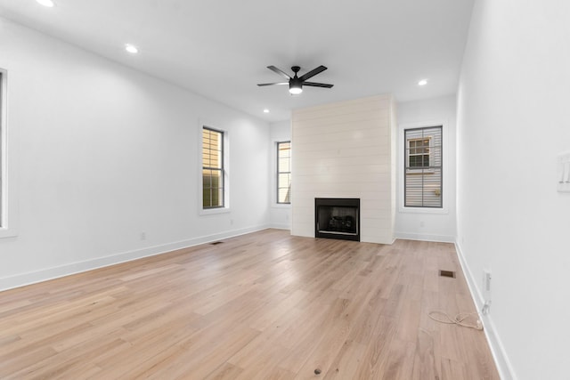 unfurnished living room with a large fireplace, baseboards, light wood finished floors, and recessed lighting