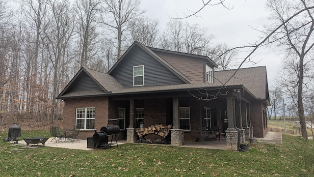 rear view of house with a fireplace, a lawn, and a patio