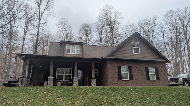 craftsman inspired home featuring brick siding, a front yard, and a shingled roof