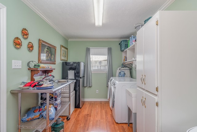 washroom with cabinet space, light wood-style flooring, crown molding, a textured ceiling, and separate washer and dryer