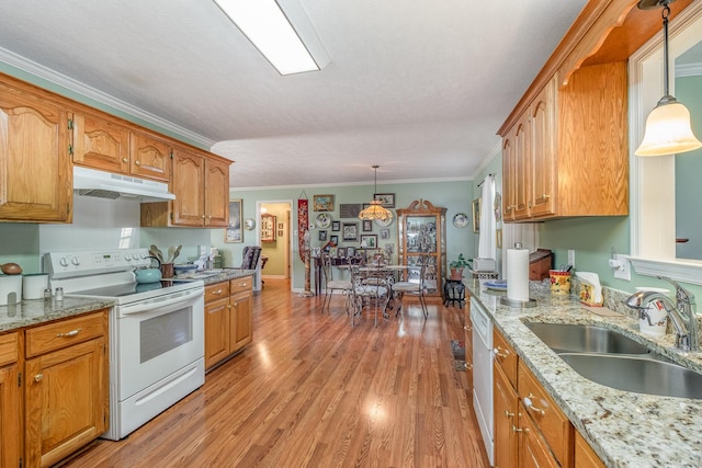 kitchen with white appliances, light wood-style floors, brown cabinets, under cabinet range hood, and a sink