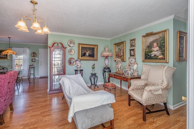 living area featuring a chandelier, a textured ceiling, wood finished floors, and crown molding