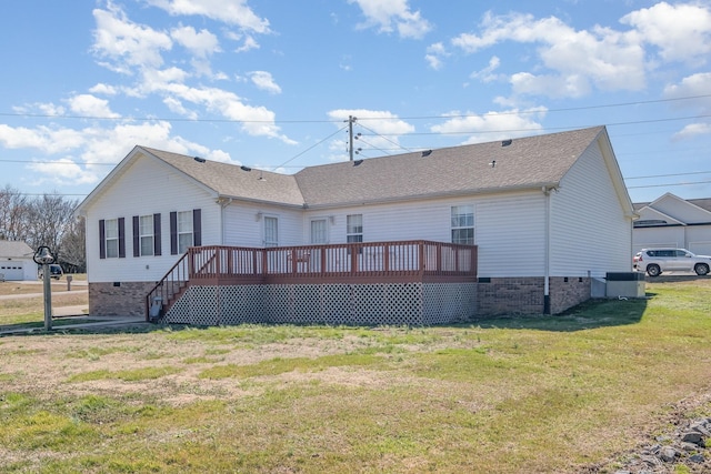 rear view of property with crawl space, roof with shingles, a yard, and a deck