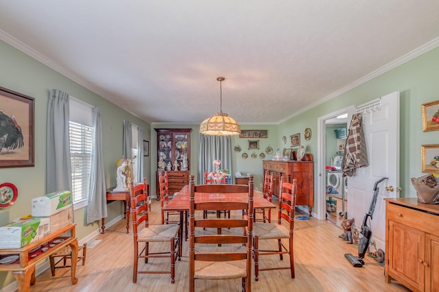 dining space with light wood-style floors, ornamental molding, and baseboards