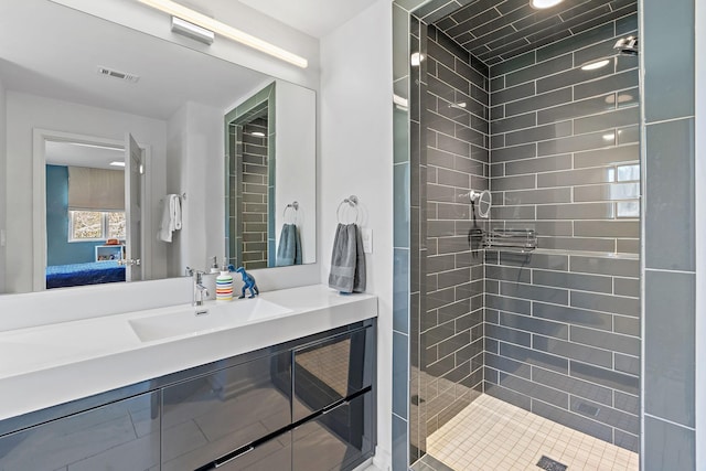 ensuite bathroom with visible vents, a tile shower, vanity, and ensuite bathroom