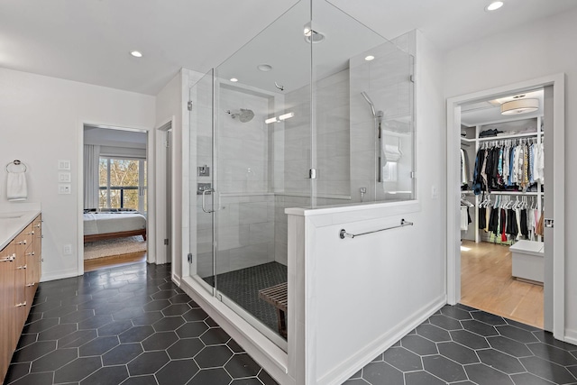 ensuite bathroom with a stall shower, recessed lighting, a walk in closet, and tile patterned floors