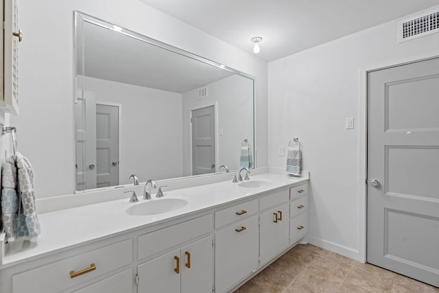 full bath with double vanity, a sink, visible vents, and baseboards