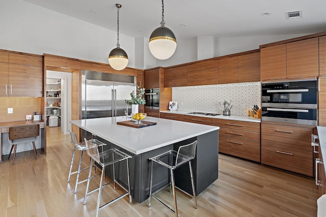 kitchen with brown cabinets, a breakfast bar, stainless steel appliances, and a center island