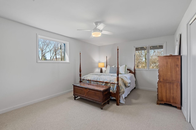 bedroom with a ceiling fan, light colored carpet, baseboards, and multiple windows